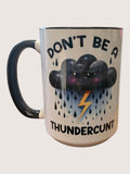 Mug with a cloud and lightning design and text 'DON'T BE A THUNDERCUNT' on a white background