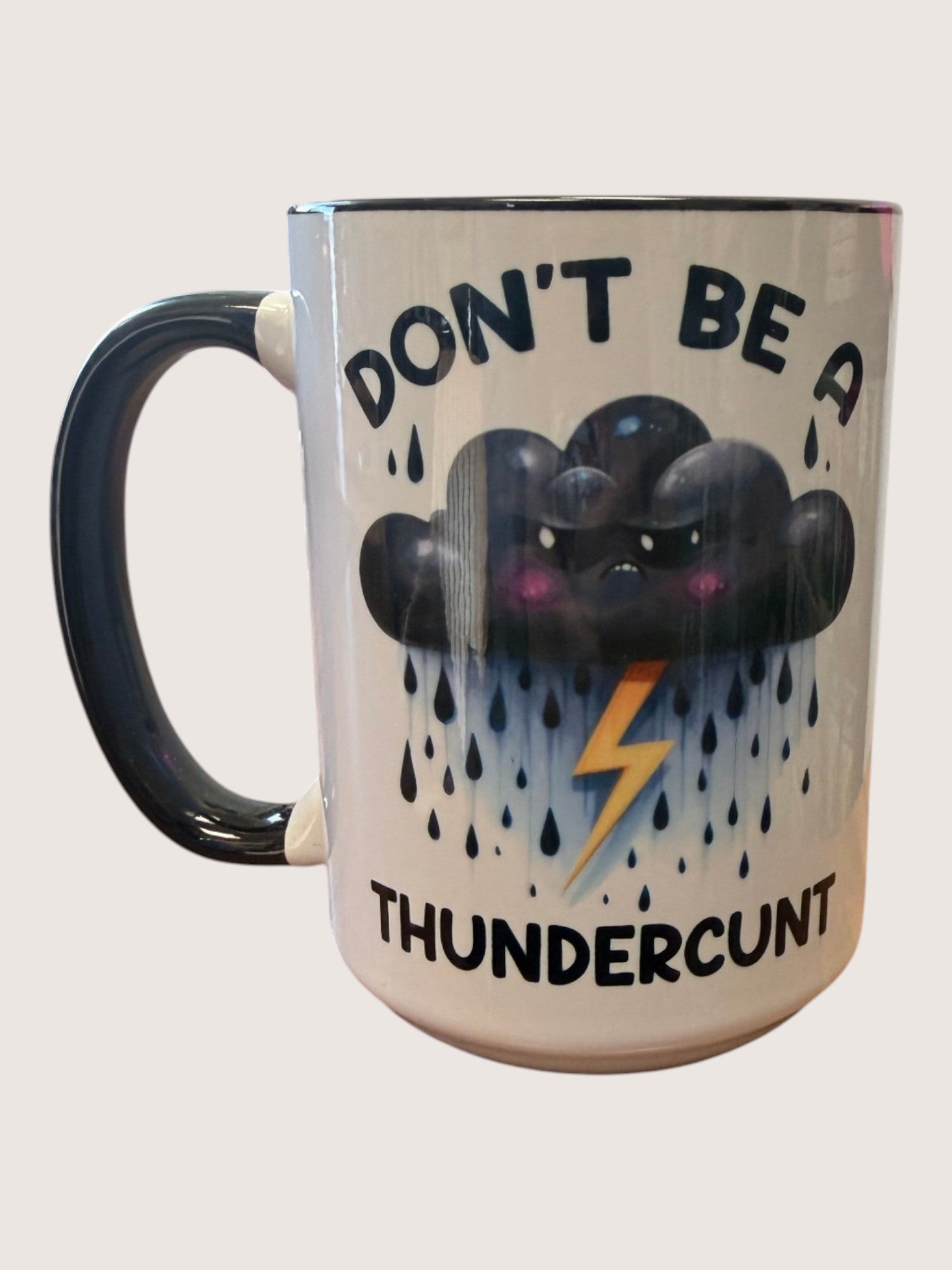 Mug with a cloud and lightning design and text 'DON'T BE A THUNDERCUNT' on a white background
