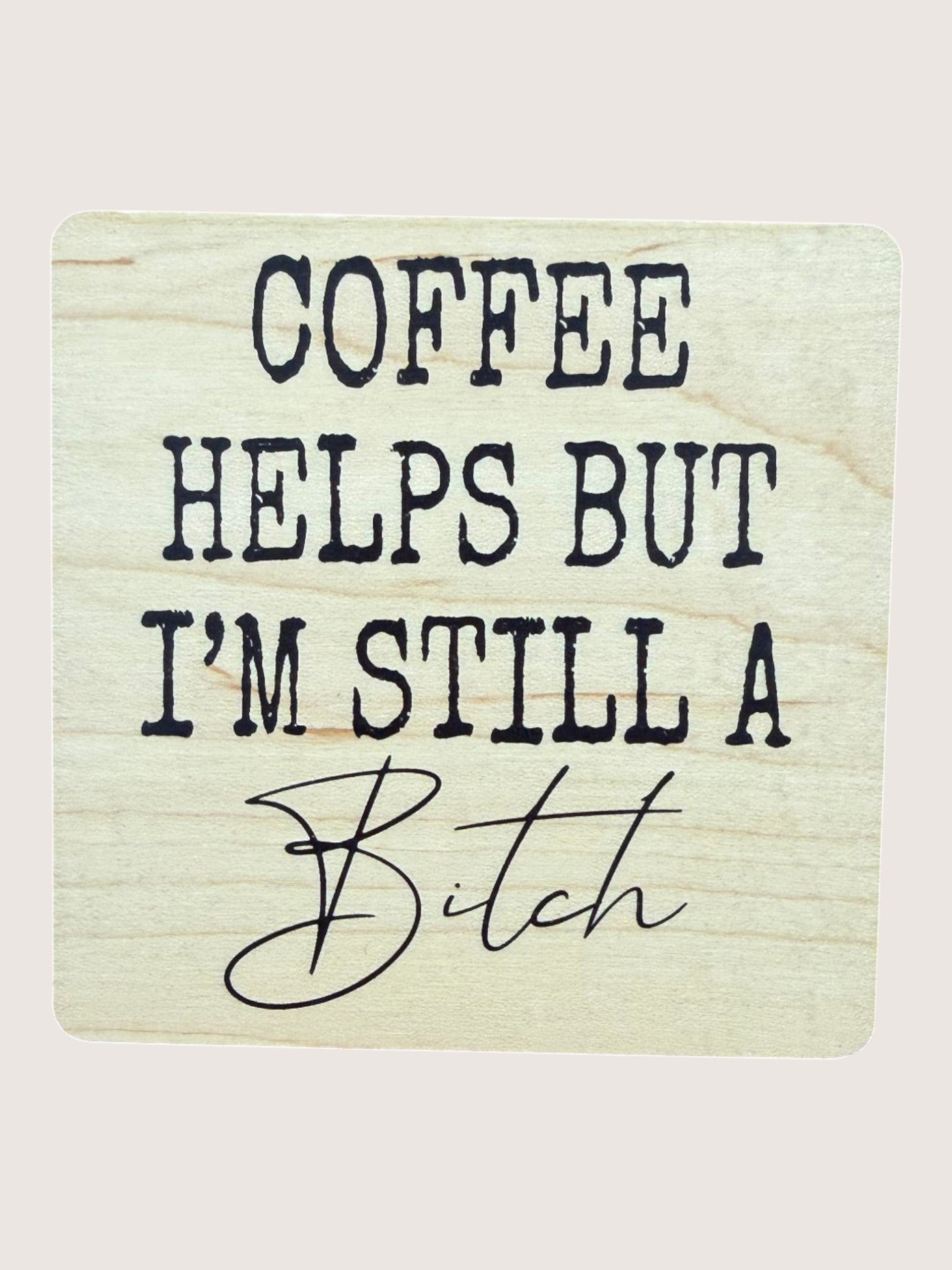 Wooden Coaster with text 'COFFEE HELPS BUT I'M STILL A BITCH' on a light background