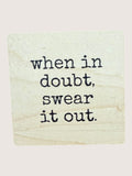 Wooden coaster with text 'when in doubt, swear it out' on a light background