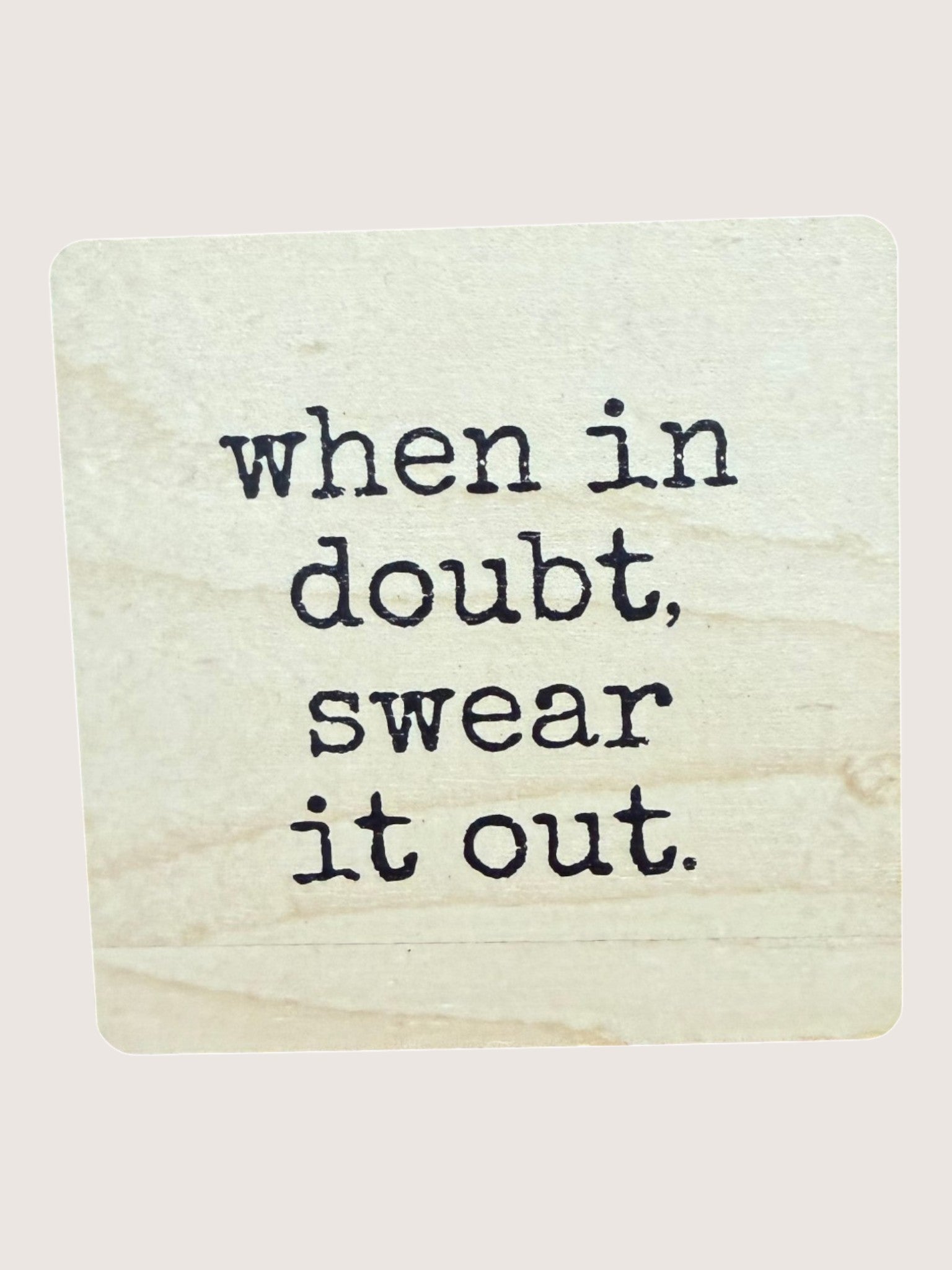 Wooden coaster with text 'when in doubt, swear it out' on a light background