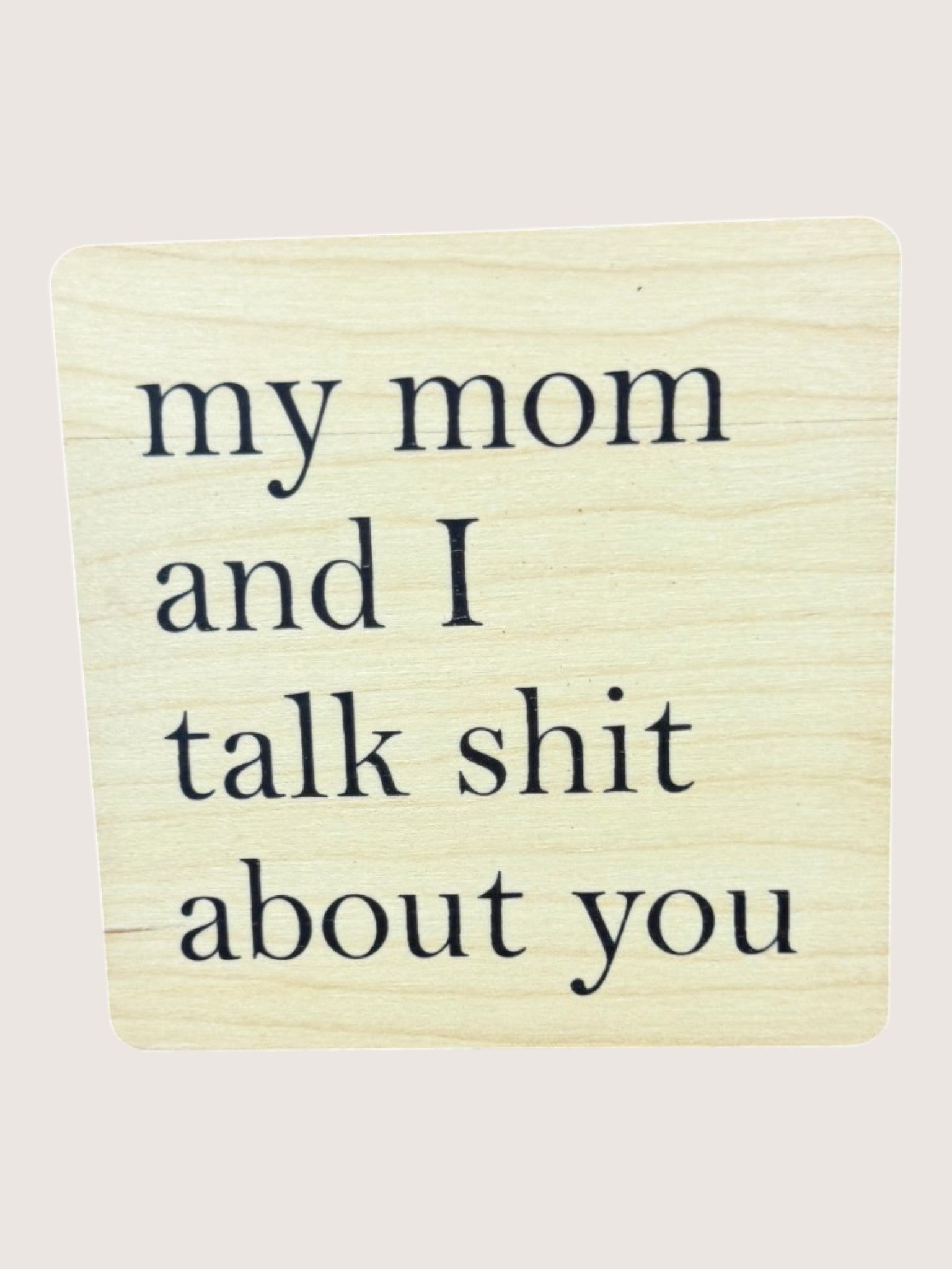 Wooden coaster with text 'my mom and I talk shit about you' on a light background
