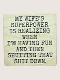 Wooden coaster with humorous text about a wife's superpower on a light background