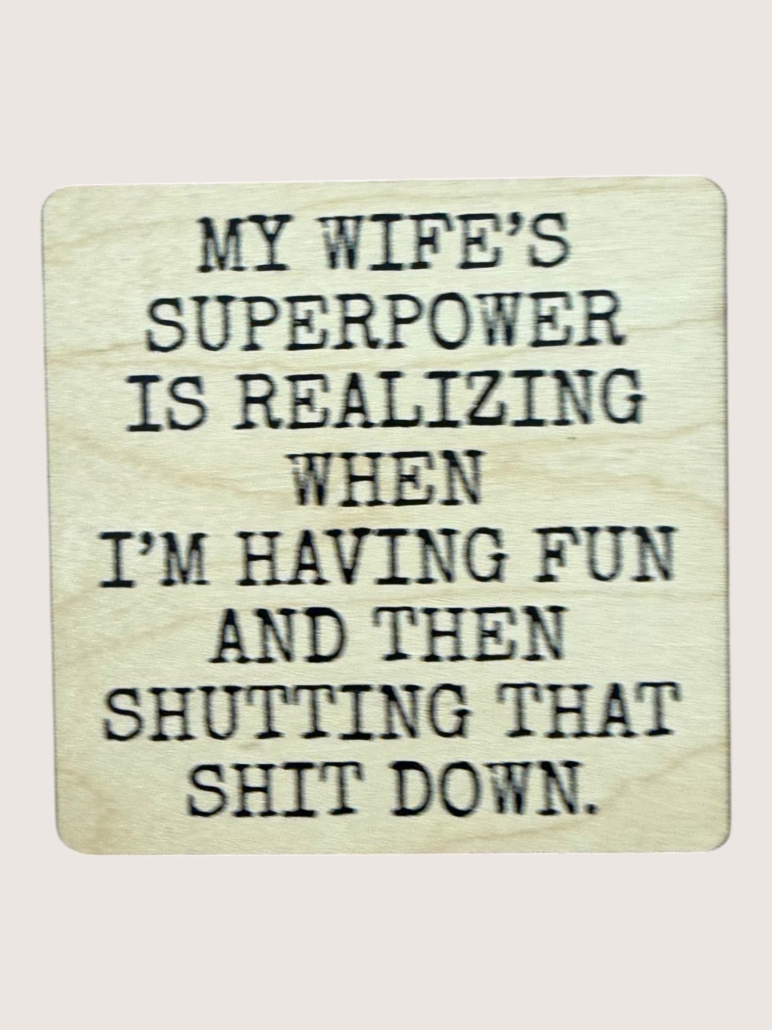 Wooden coaster with humorous text about a wife's superpower on a light background