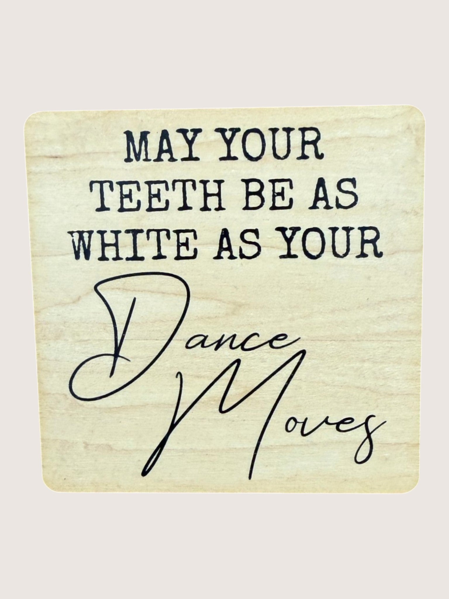 Wooden coaster with humorous dental and dance-themed text on a beige background