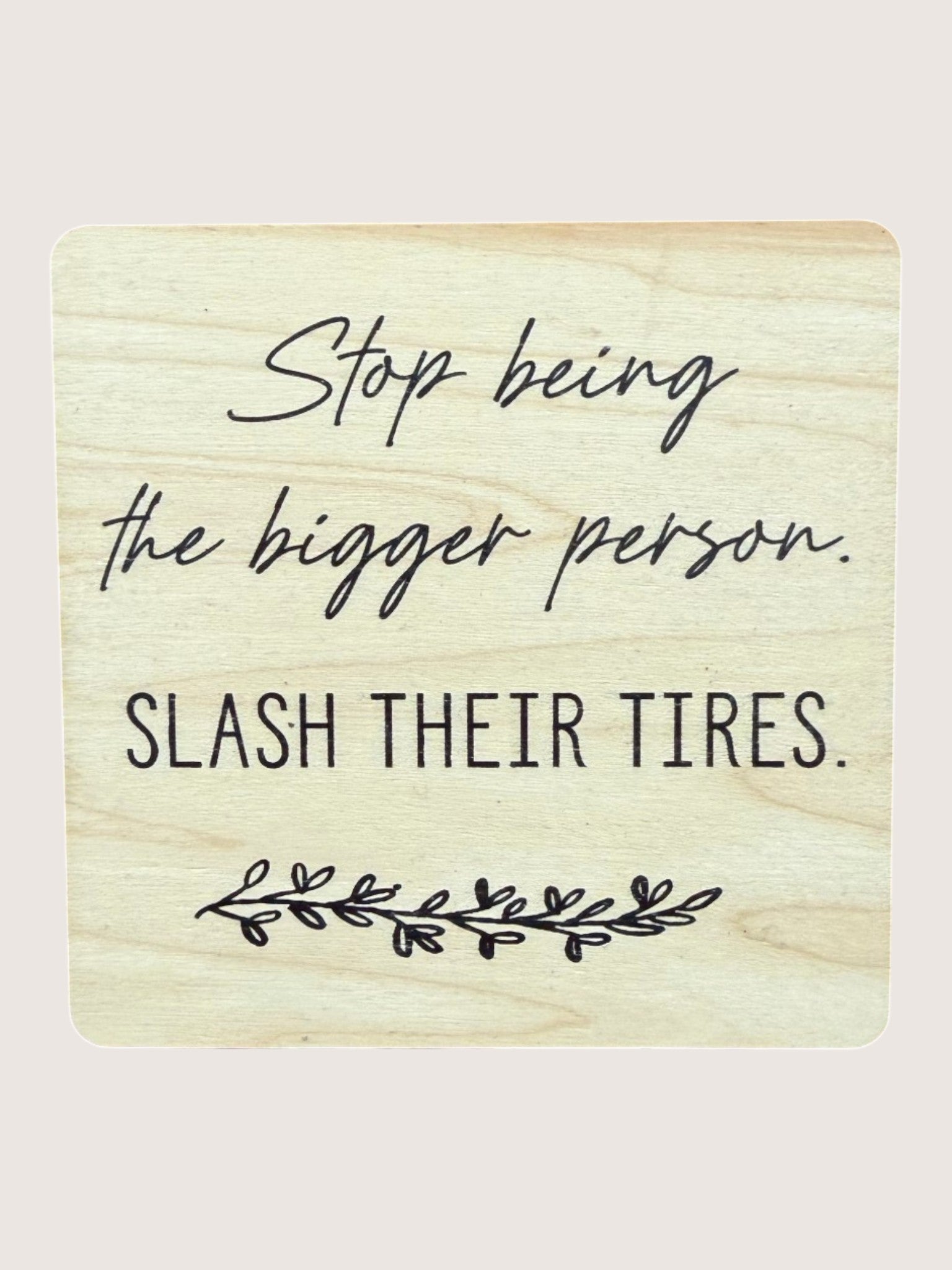 Wooden coaster with humorous text 'Stop being the bigger person, slash their tires.'