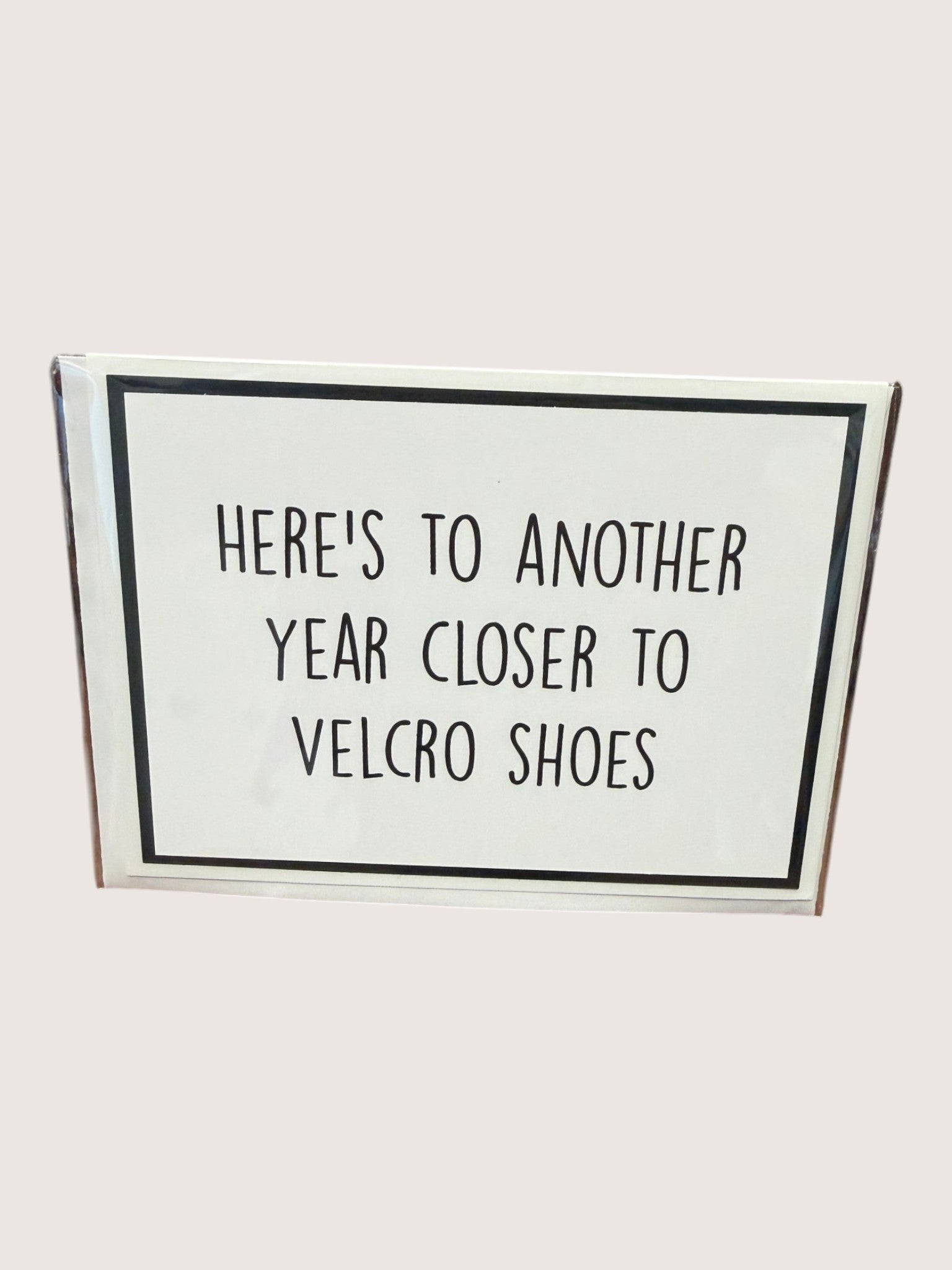 Card with text 'Here's to another year closer to velcro shoes' on a white background