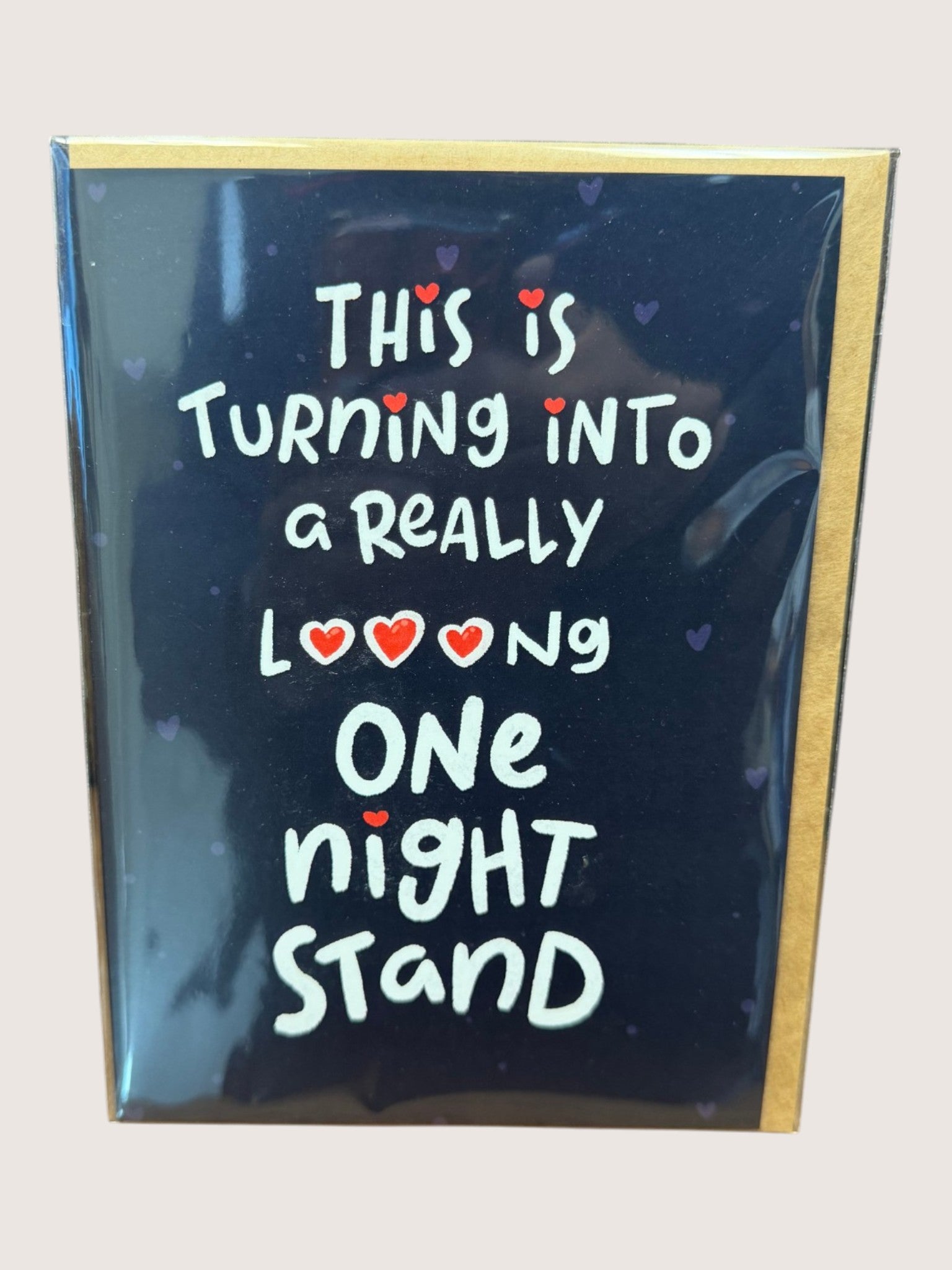 Card with text 'This is turning into a really long one night stand' on a reflective surface.