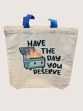 Tote bag with 'Have the day you deserve' text and trash bin graphic on a white background
