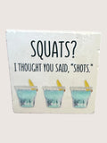 coaster with 'SQUATS? I Thought You Said, 'Shots.'' text and shot glass illustrations.