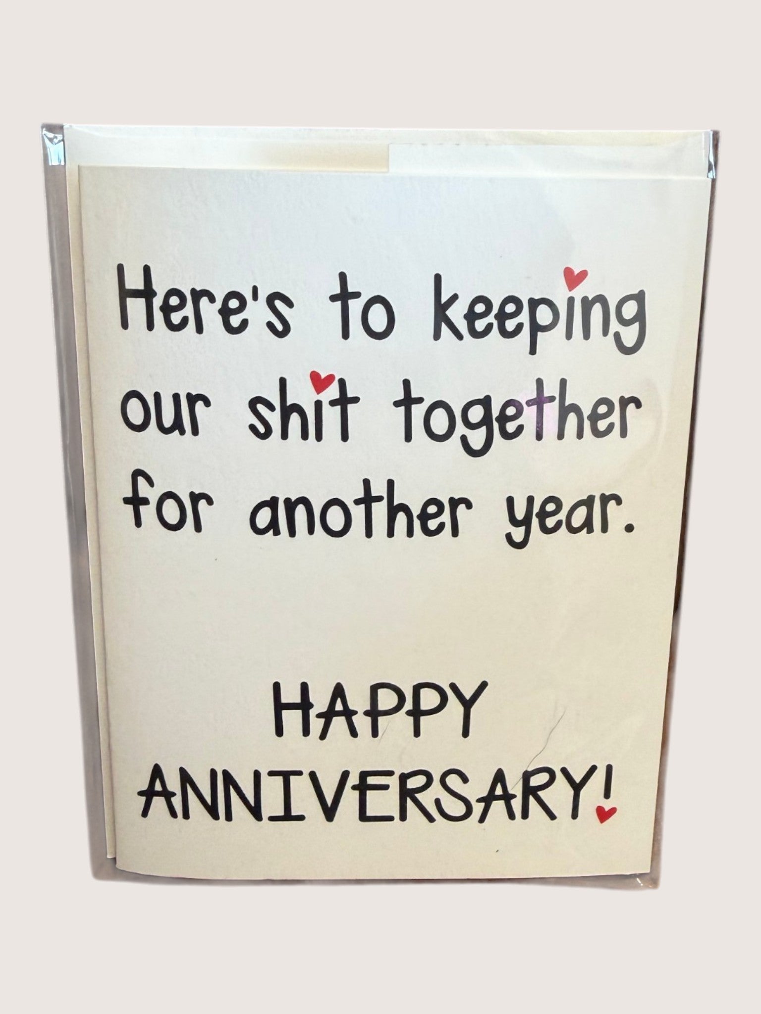 card with text 'here's to keeping our shit together for another year. Happy anniversary!'