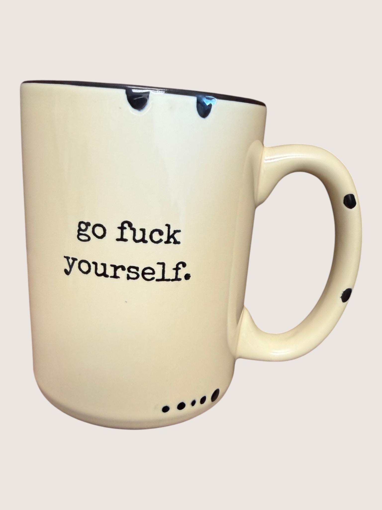 Beige mug with black text 'go fuck yourself.' on a white background
