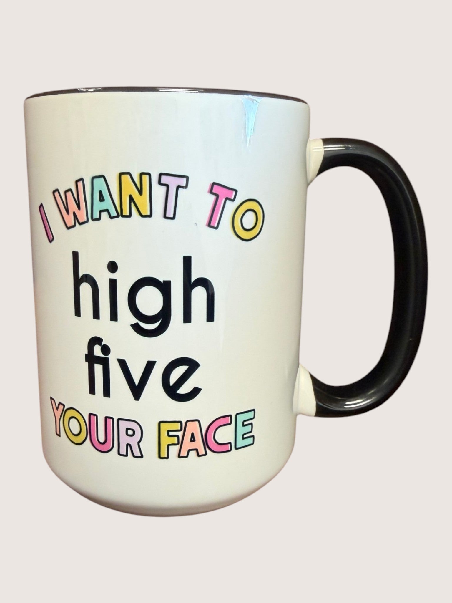 White mug with colorful text 'I want to high five your face' on a white background