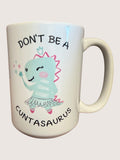 Mug with cartoon character and text 'Don't be a Cuntasaurus' on a light background