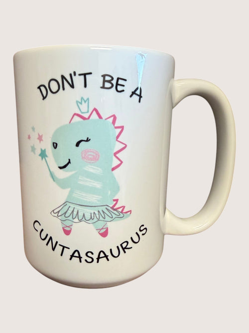 Mug with cartoon character and text 'Don't be a Cuntasaurus' on a light background