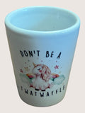 white shot glass with a unicorn illustration and text on a light pink background