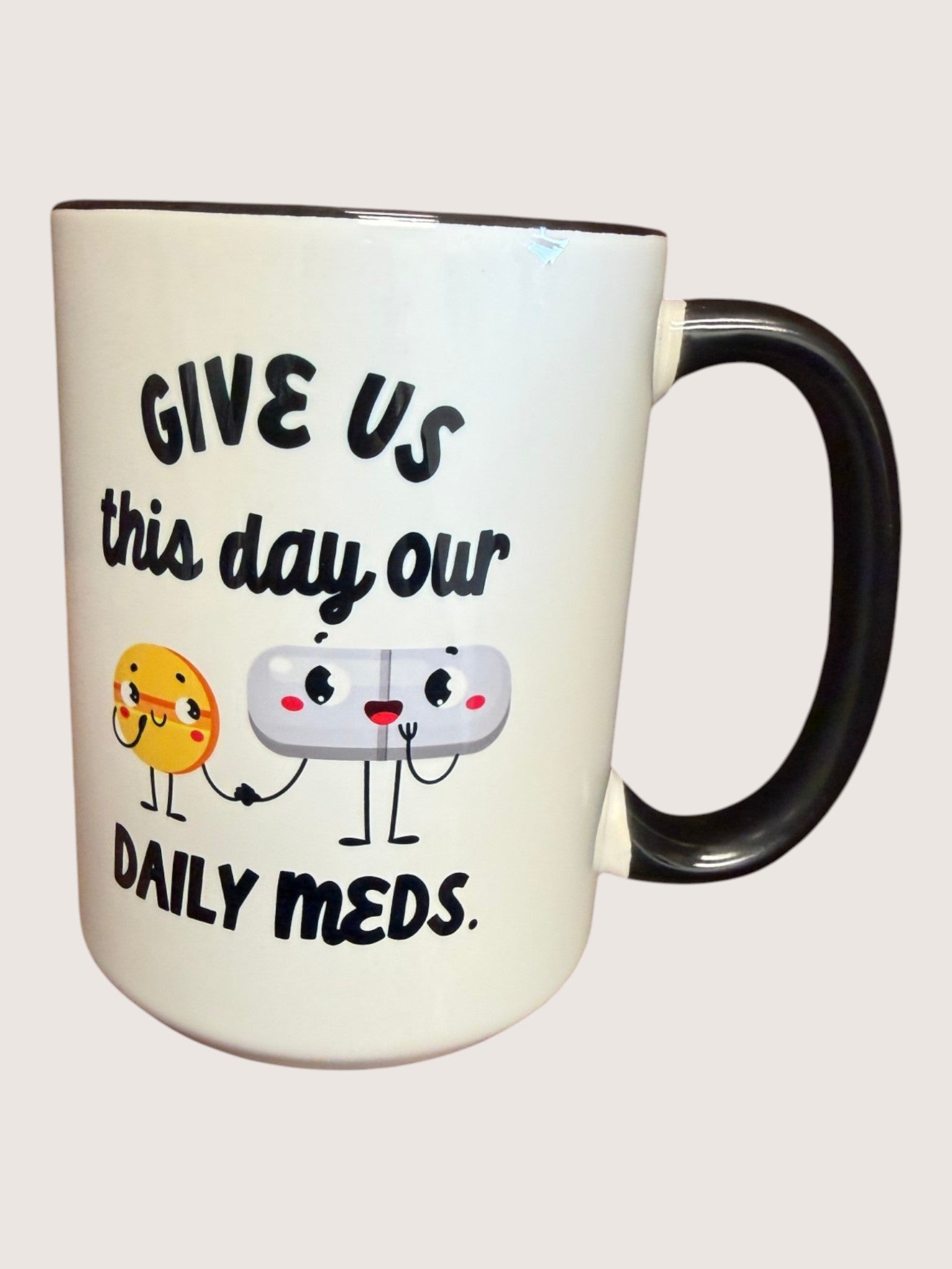 Mug with cartoon characters and text 'Give us this day our daily meds' on a white background
