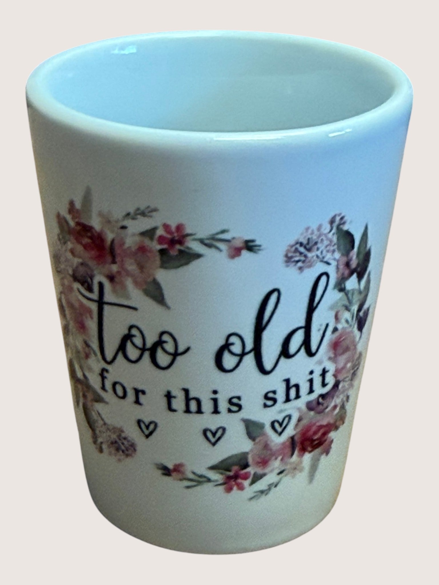 shot glass with floral design and text on a plain background