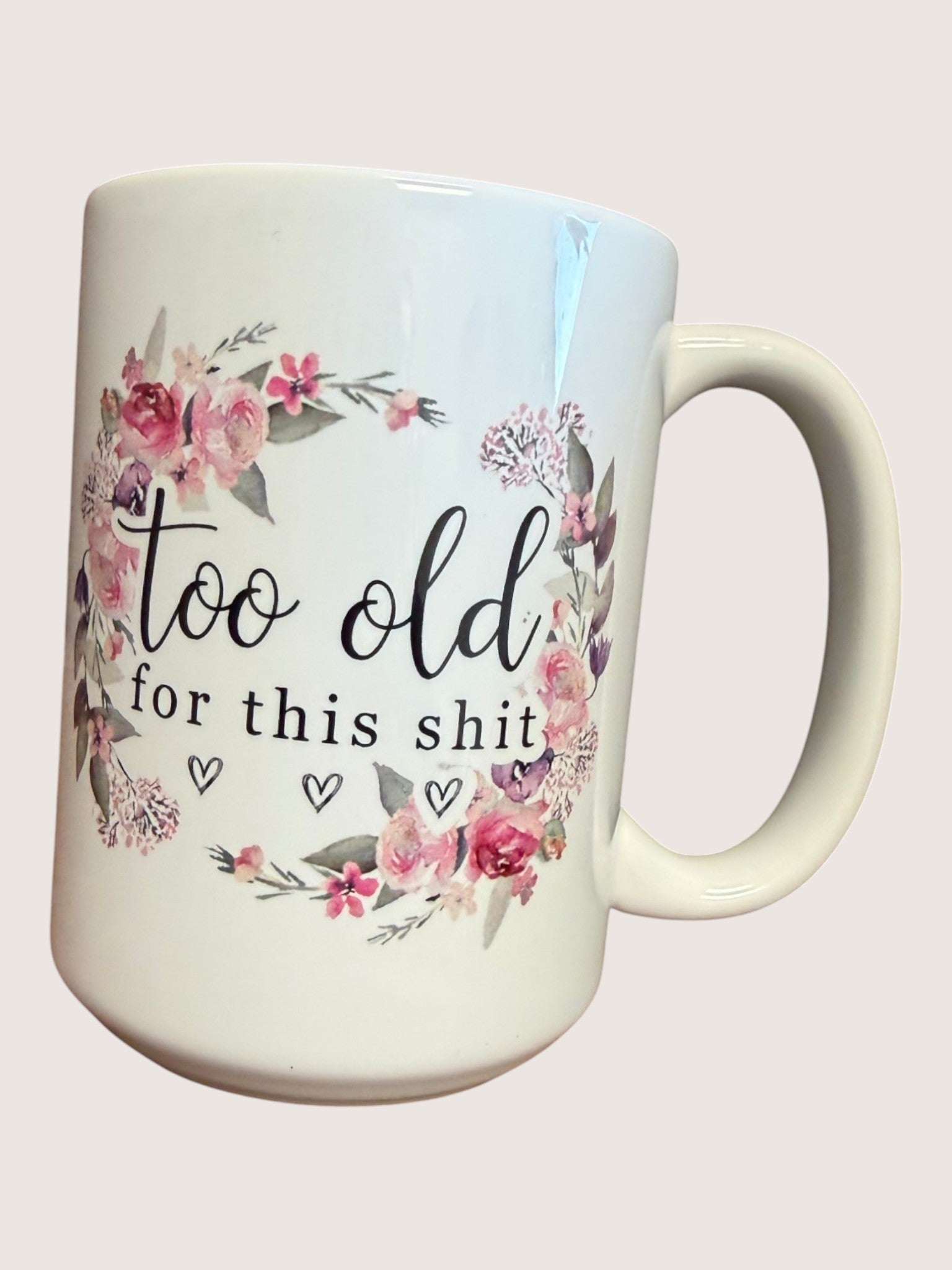 Mug with floral design and text 'too old for this shit' on a white background
