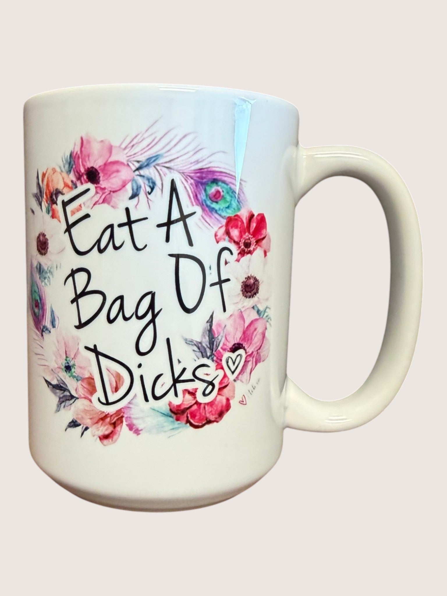 Mug with floral design and offensive text on a white background