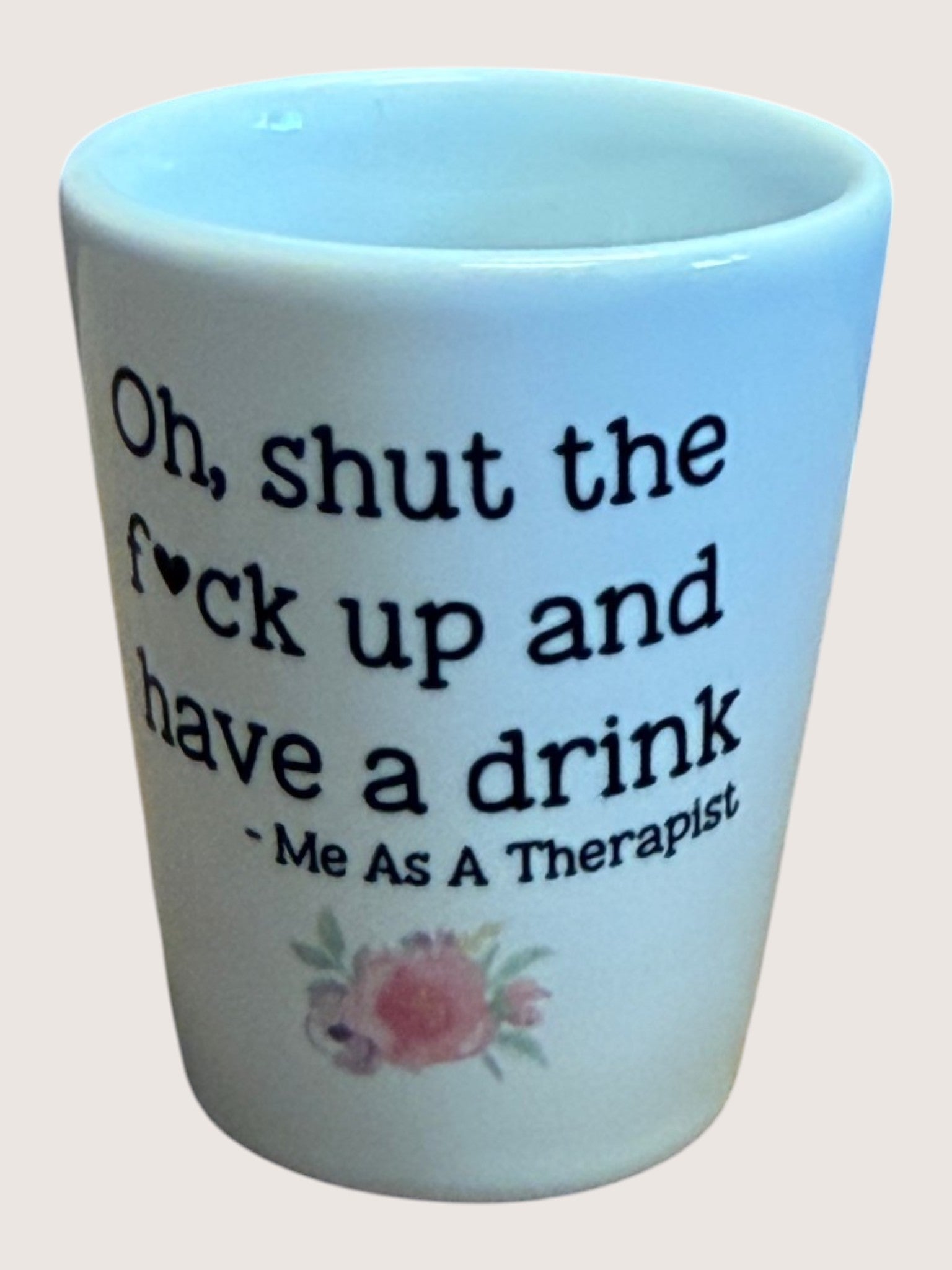 shot glass with text 'Oh, shut the f*ck up and have a drink - Me As A Therapist' and floral design on a light blue background