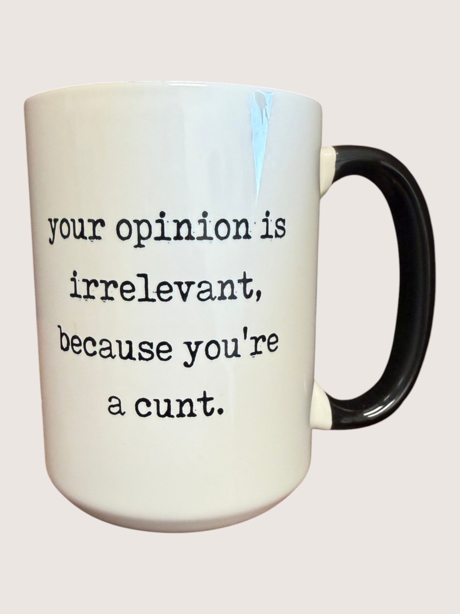 Mug with text 'your opinion is irrelevant, because you're a cunt.' on a plain background