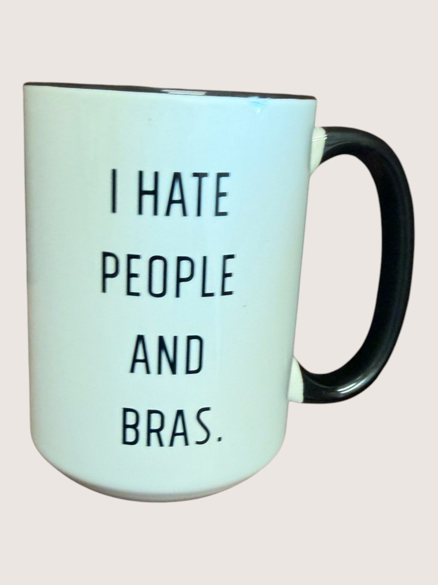 Mug with text 'I HATE PEOPLE AND BRAS' on a light pink background
