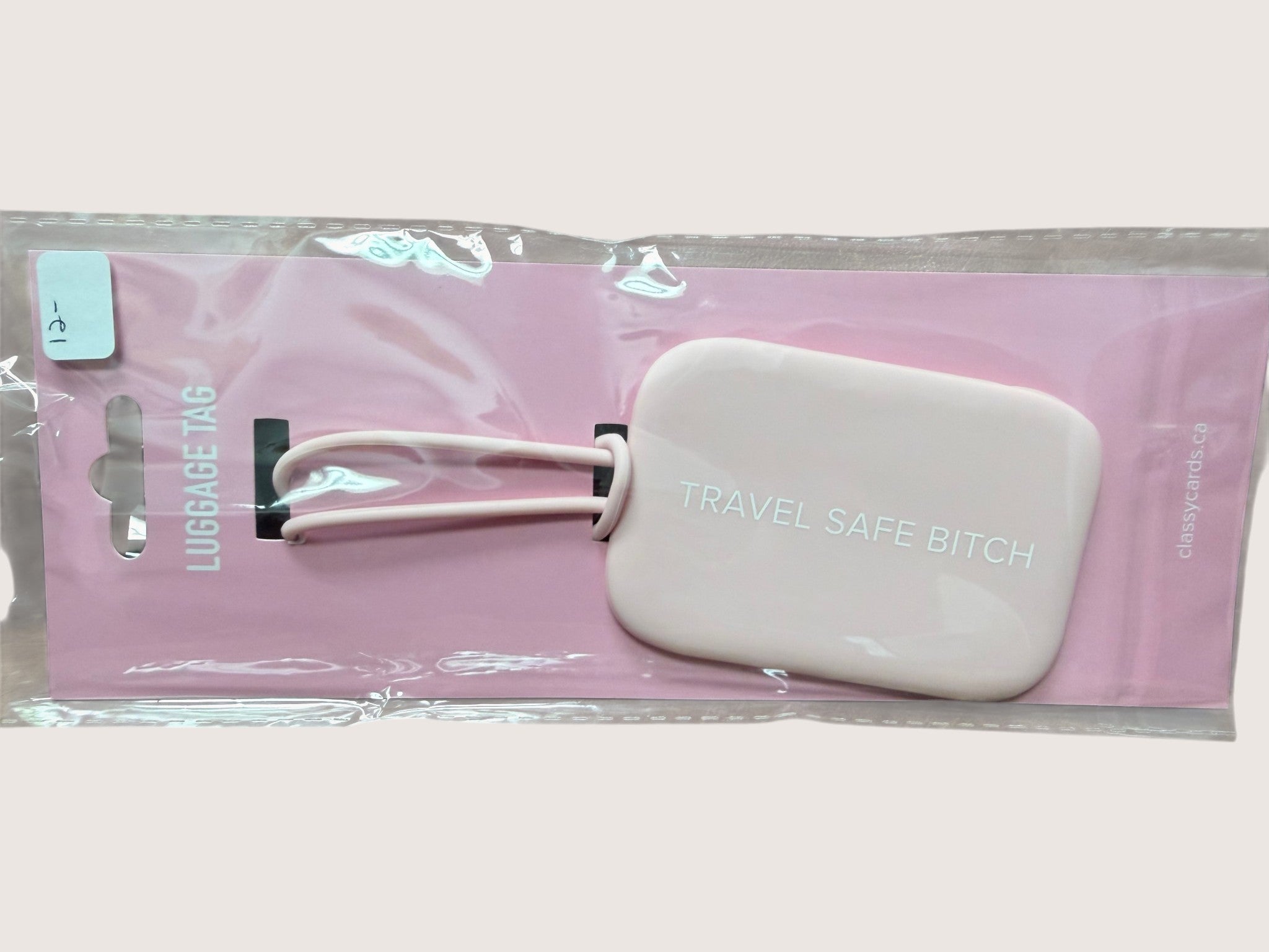 Pink luggage tag with text 'TRAVEL SAFE BITCH' in clear packaging