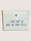 Card with text 'I love that we hate the same people' and a heart symbol on a light background