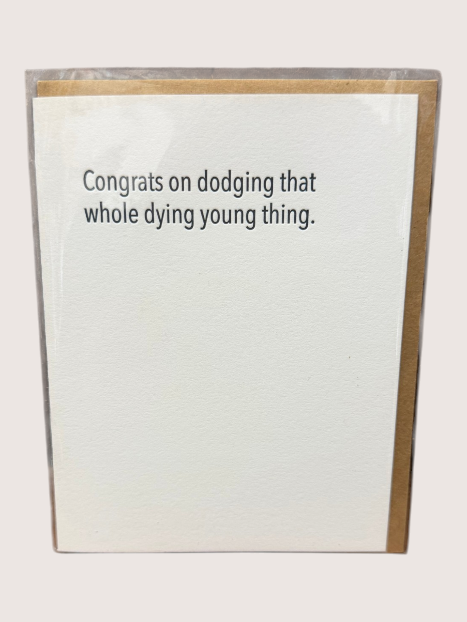 Card with humorous text 'Congrats on dodging that whole dying young thing.' on a white background.