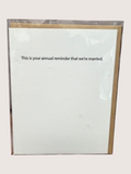 White card with gold border and text 'This is your annual reminder that we're married' on a white background