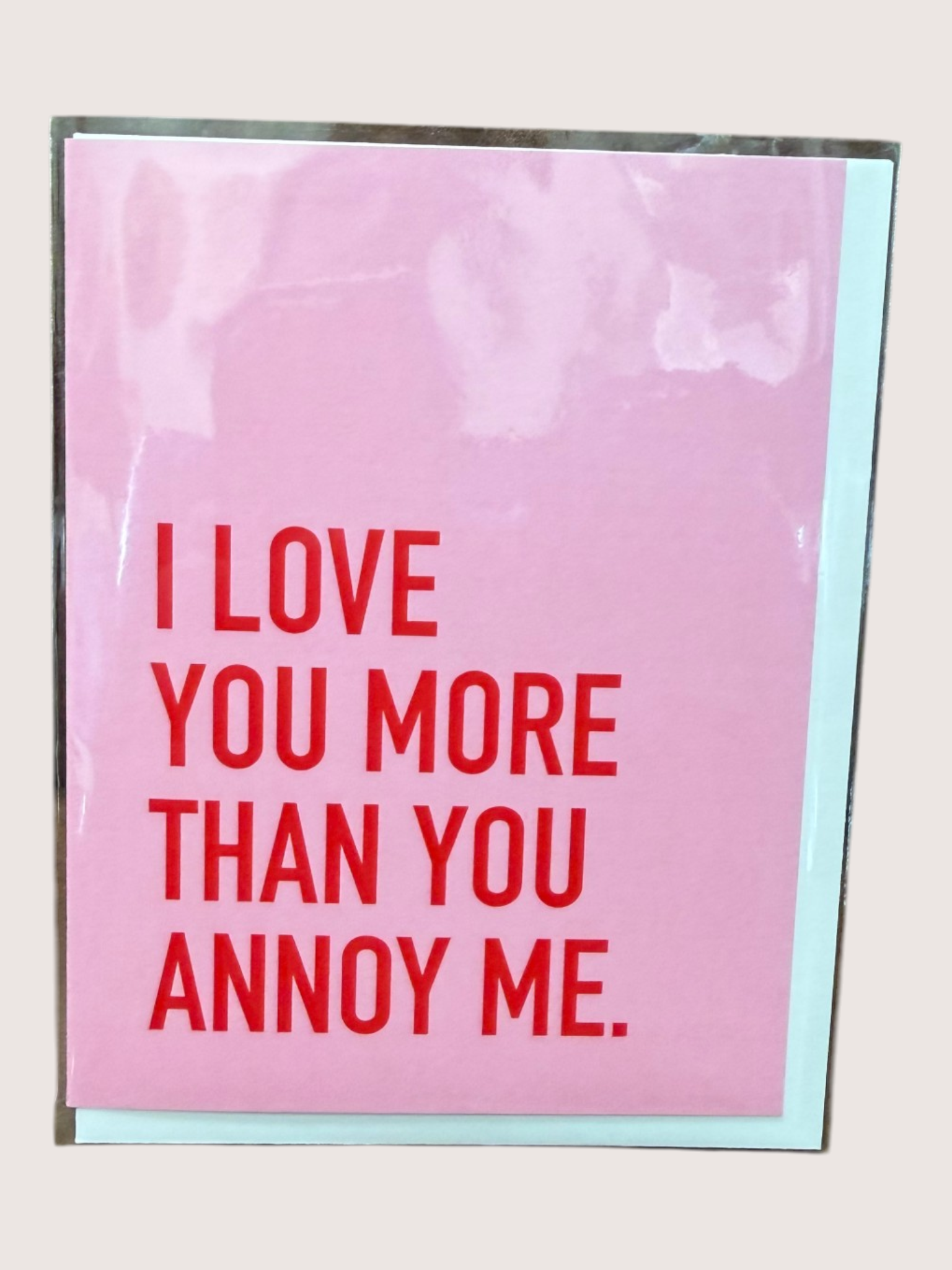 Pink card with red text 'I LOVE YOU MORE THAN YOU ANNOY ME' on a light gray background