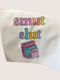 Tote bag with colorful text 'smut slut' and book illustrations on a white background