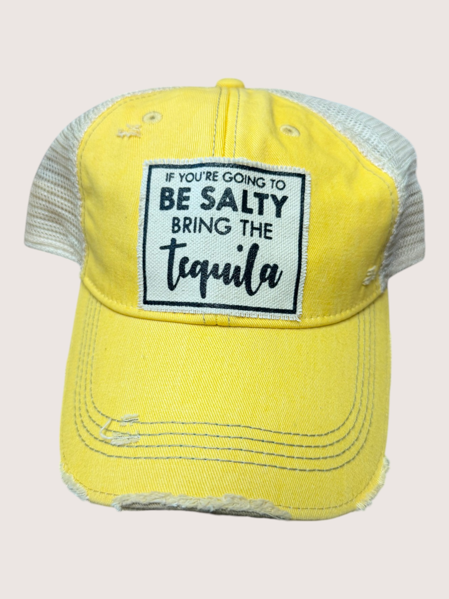 Yellow cap with text 'If you're going to be salty, bring the tequila' on a light gray background