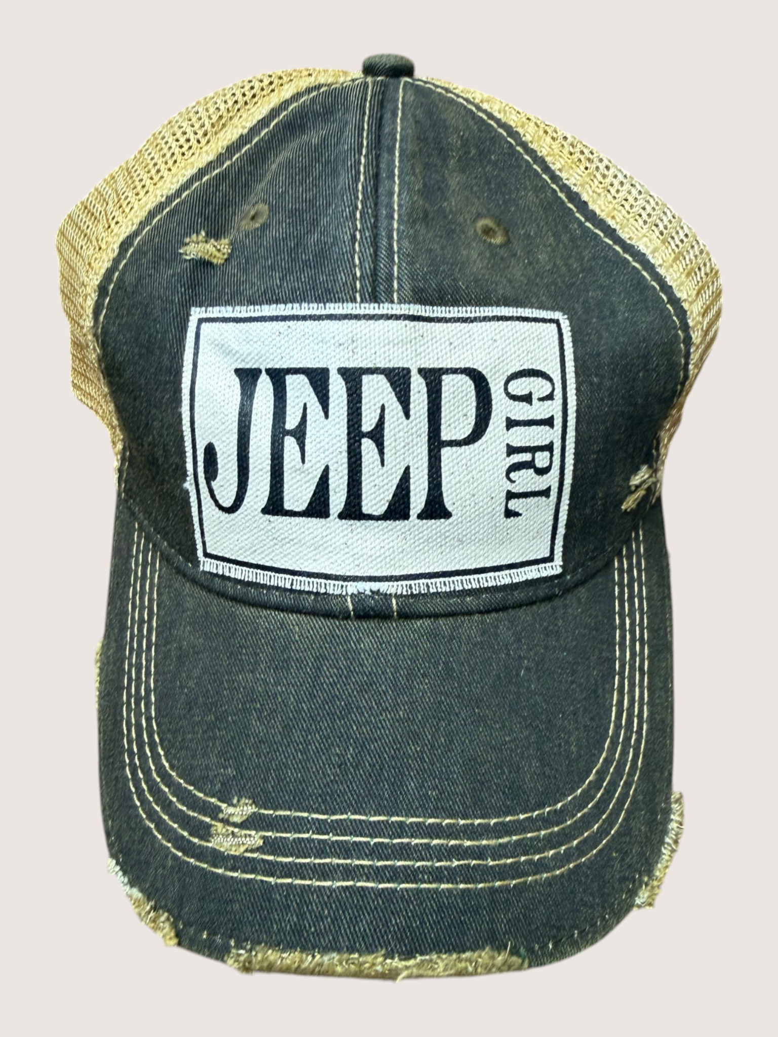 Black and gold cap with 'Jeep Girl' logo on a beige background