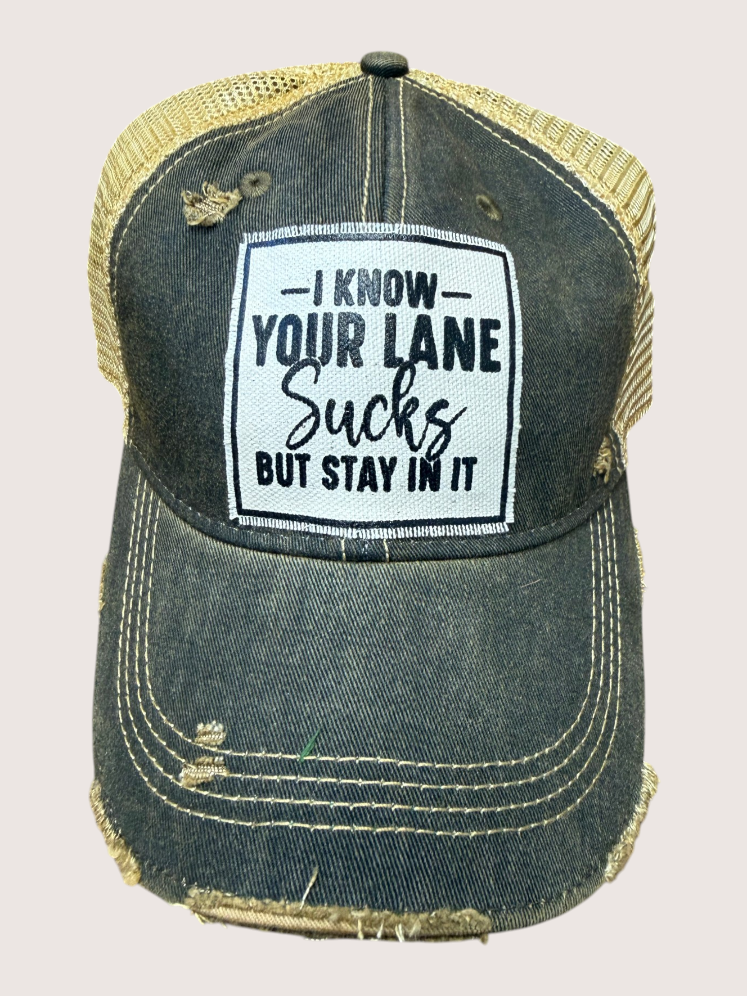 Denim cap with a humorous text patch on a light gray background
