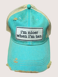 Turquoise cap with 'i'm nicer when i'm tan' patch on a light pink background