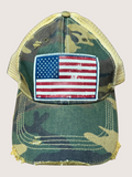 Camouflage cap with American flag patch on a light pink background