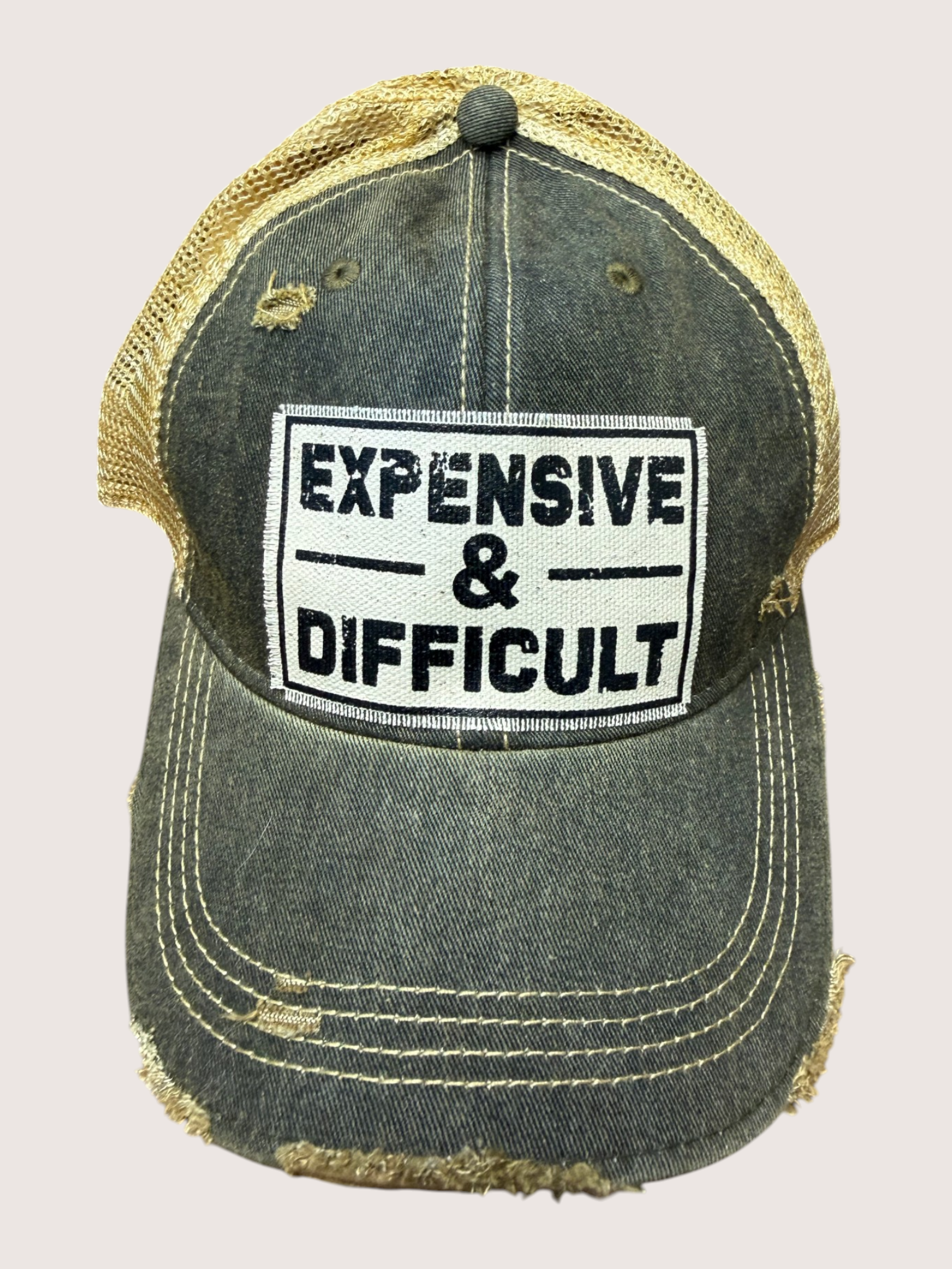 Distressed cap with 'EXPENSIVE & DIFFICULT' patch on a light gray background