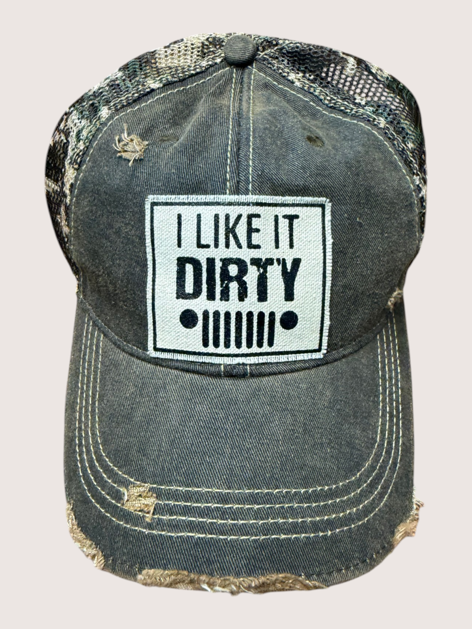 Distressed denim cap with 'I Like It Dirty' patch on a light gray background