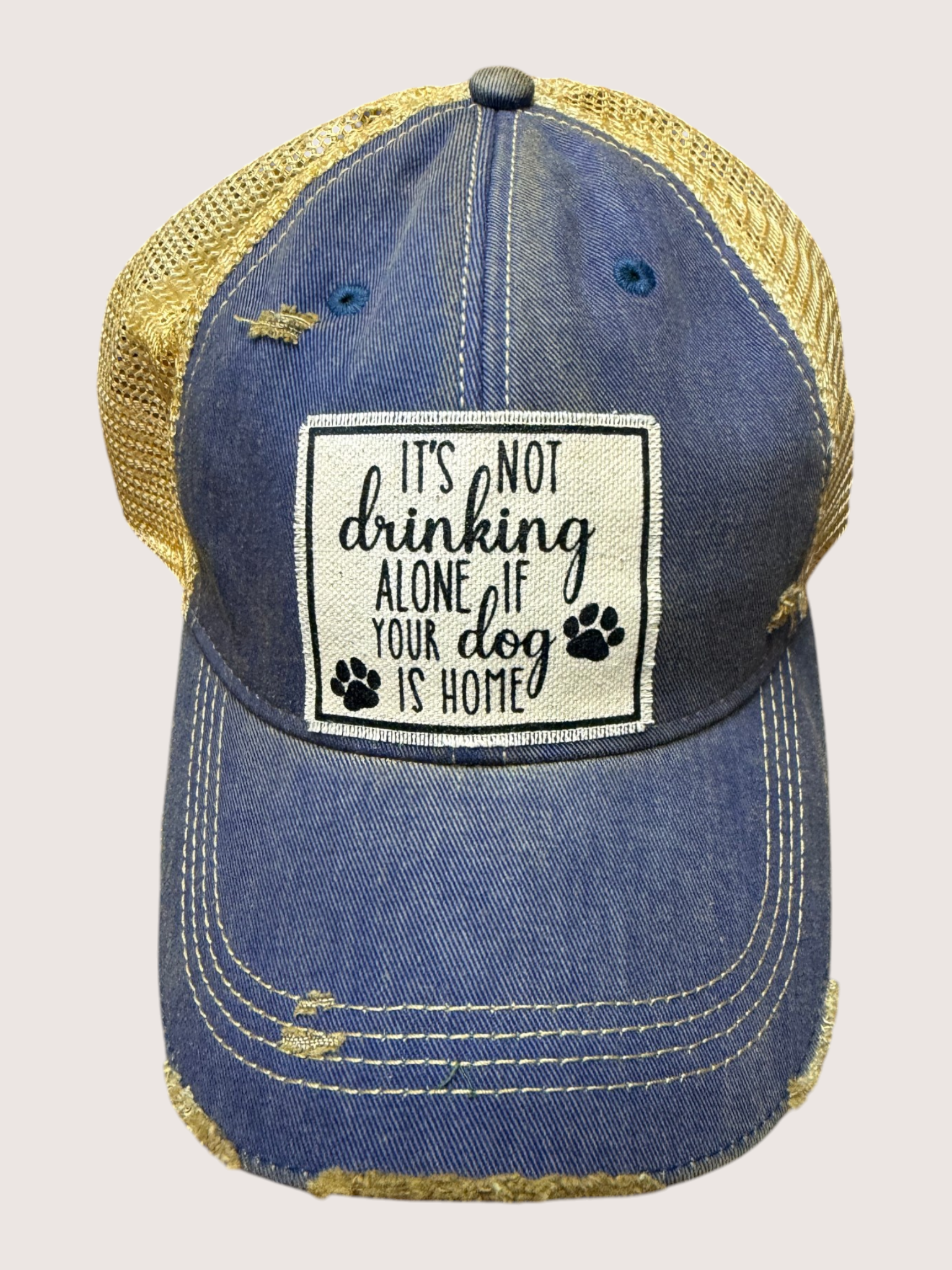 Blue denim cap with yellow mesh back and text patch on a light gray background