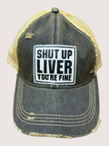 Black and yellow cap with 'Shut Up Liver You're Fine' text on a beige background