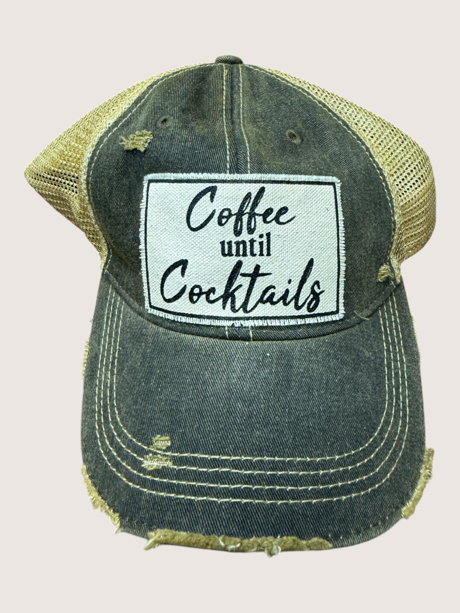 Distressed green cap with 'Coffee until Cocktails' patch on a light gray background