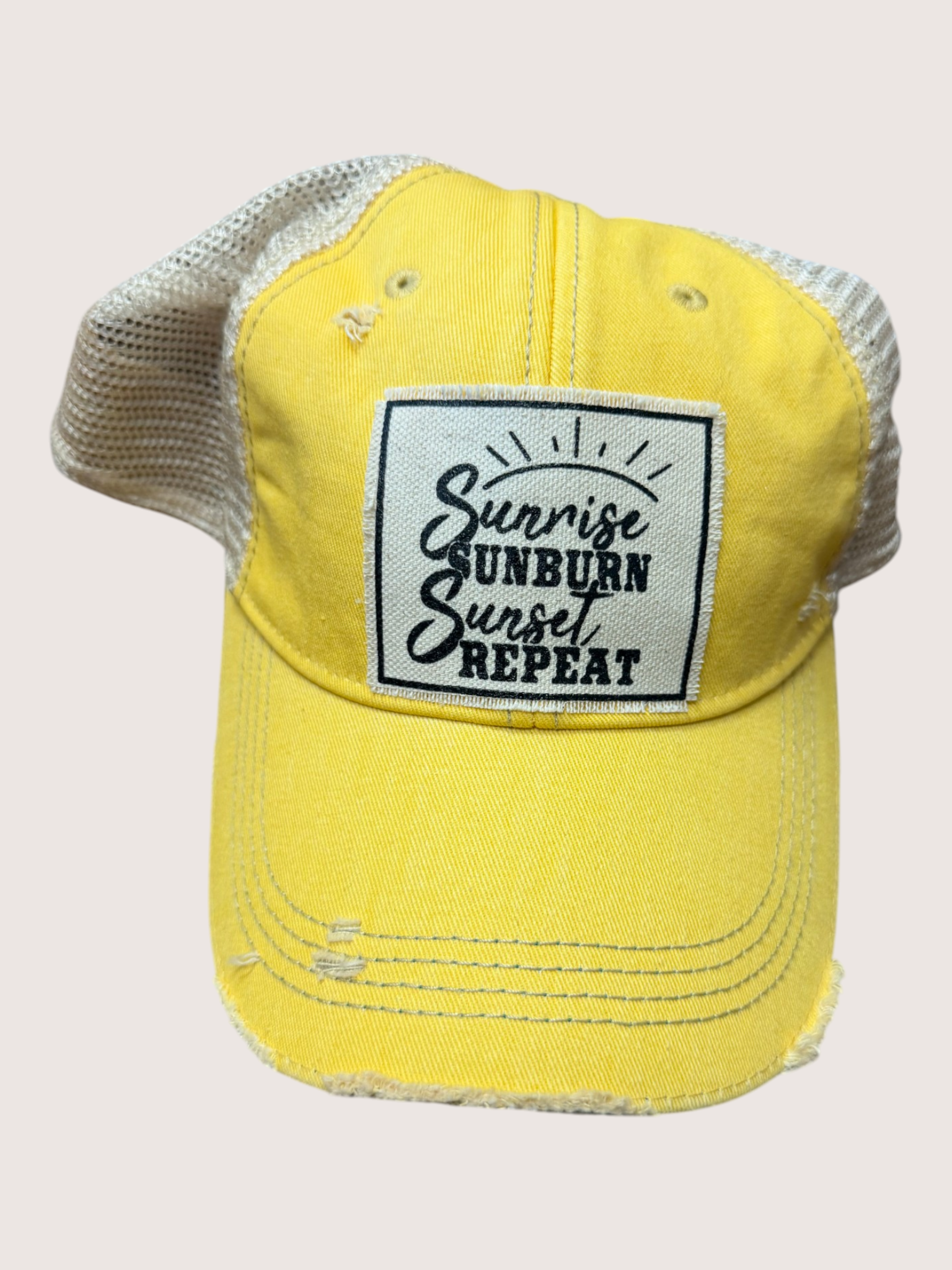 Yellow cap with a black and white patch on a light beige background