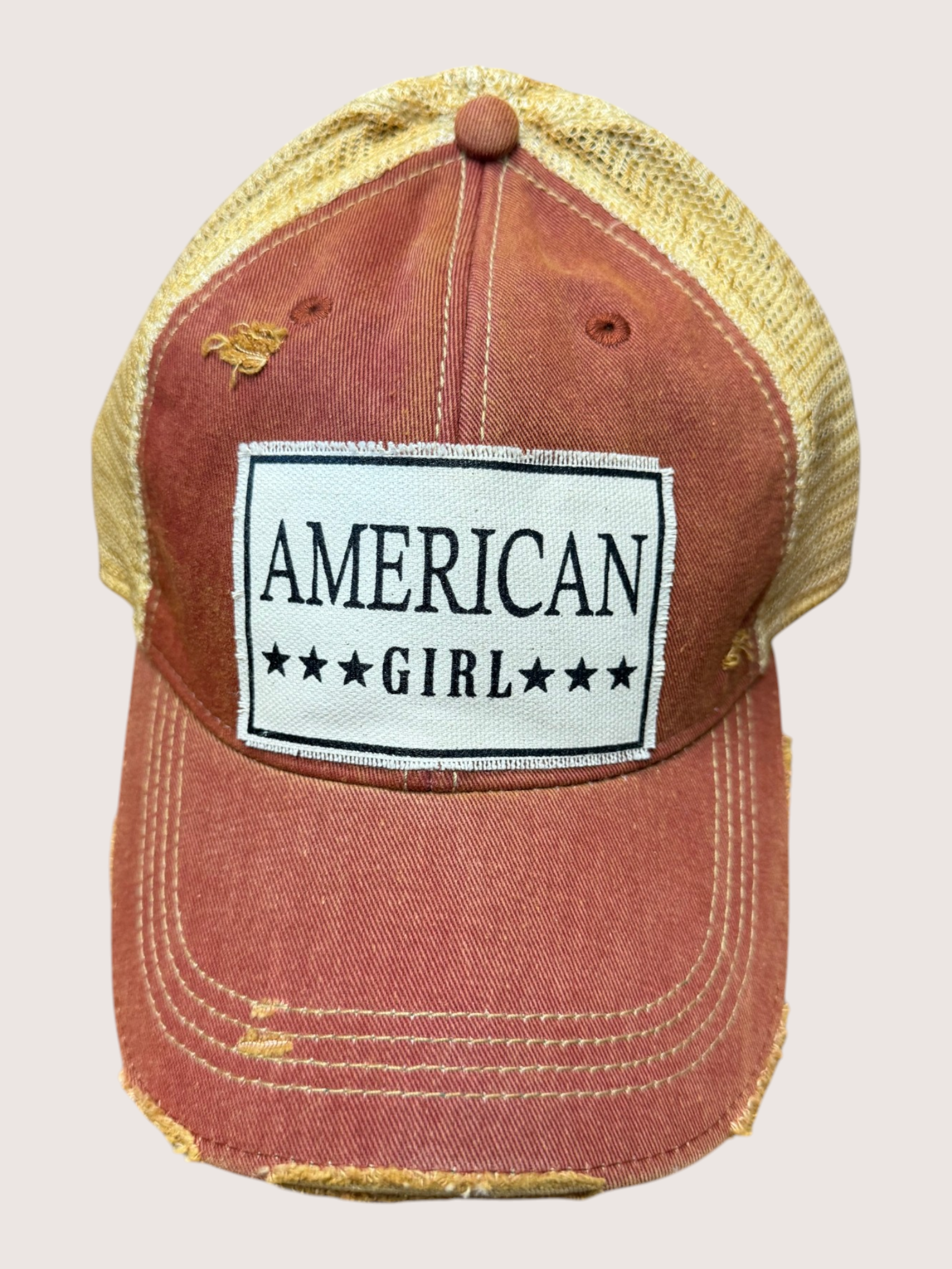 Red distressed cap with 'American Girl' patch on a light gray background