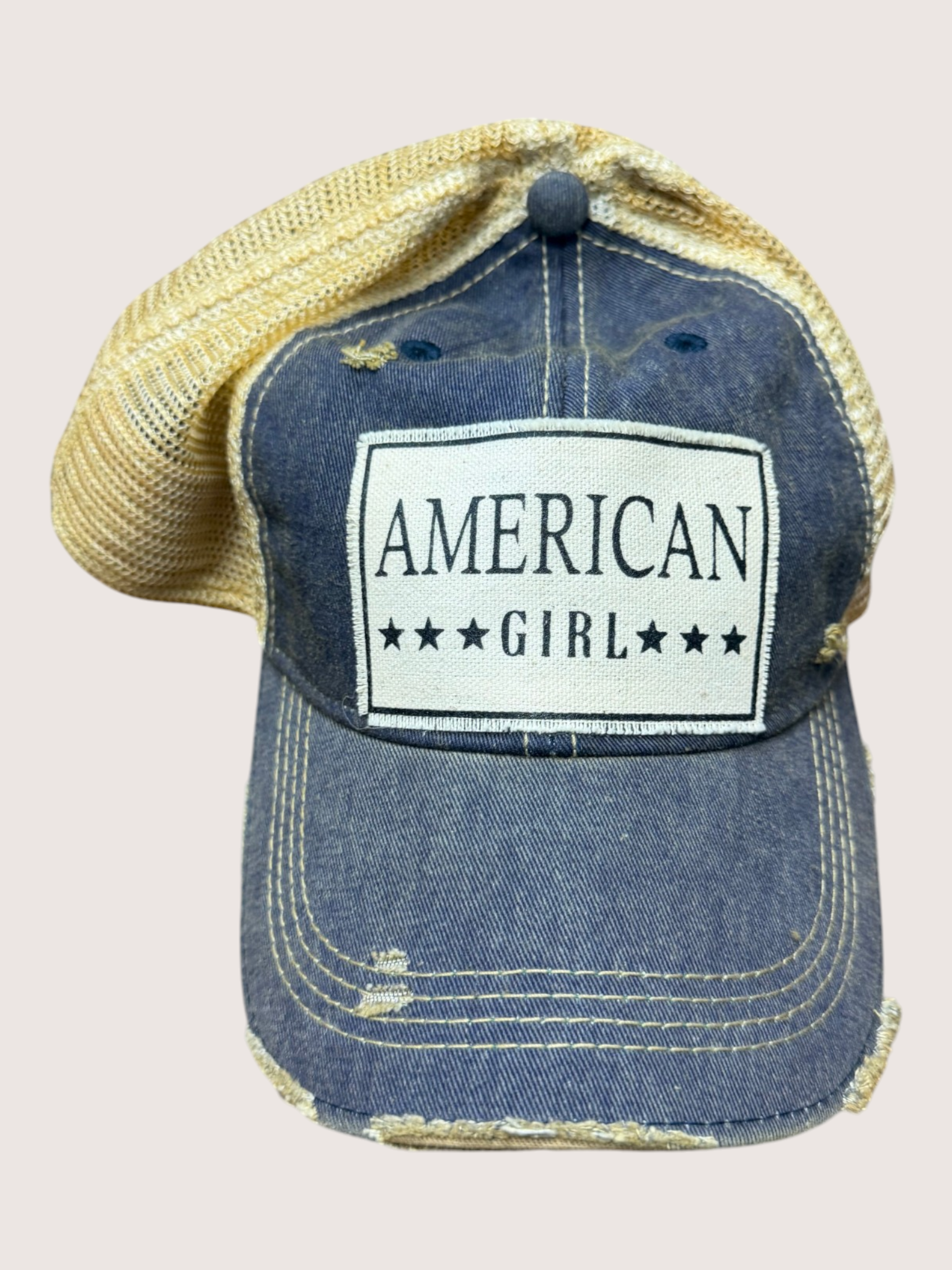 Blue denim cap with 'American Girl' logo on a light pink background