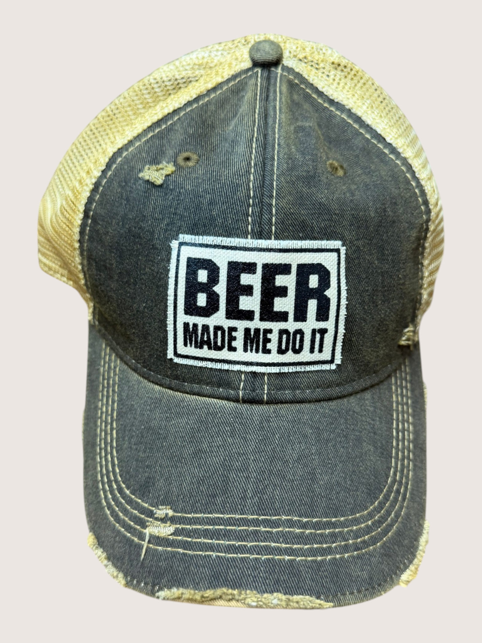 Cap with 'BEER MADE ME DO IT' text on a beige background
