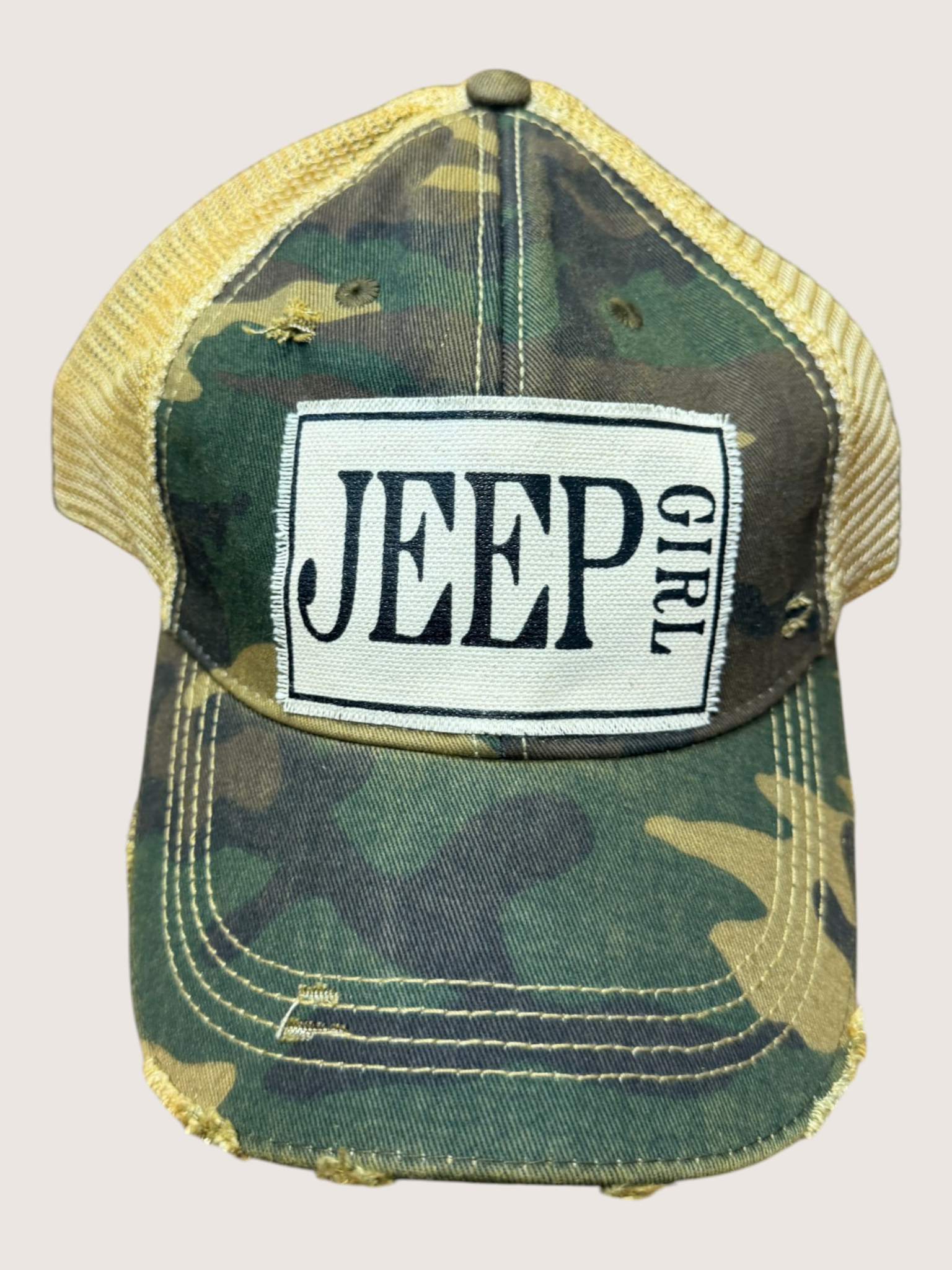Camouflage cap with 'Jeep Girl' patch on a beige background