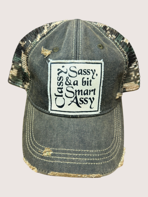 Vintage-style cap with a patch reading 'Sassy, Classy & a bit Smart Assy' on a light gray background