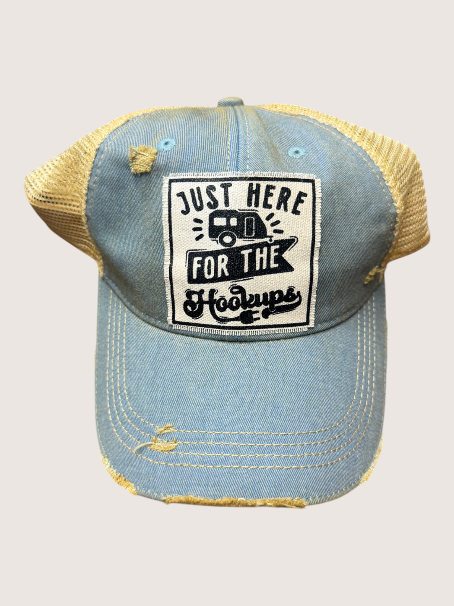 Denim cap with yellow rim and 'Just Here for the Hooters' text on a light gray background